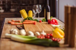 Frisches Gemüse, Flasche Wein und Gläser auf dem Küchentisch