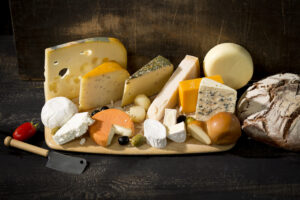 Käseplatte mit verschiedenen Sorten von Käse auf einem rustikalen Holzbrett.