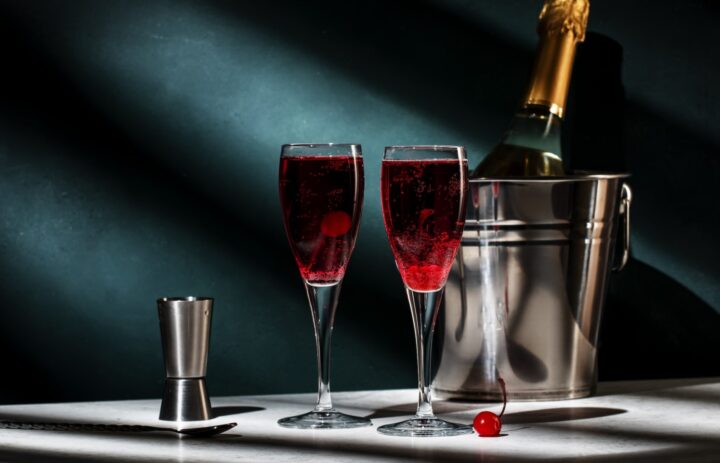 Kir Royale Cocktail mit schwarzem Johannisbeerlikör, Champagner und roter Cocktailkirsche