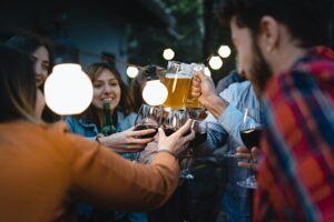 Menschen prosten sich mit Bier und Wein zu